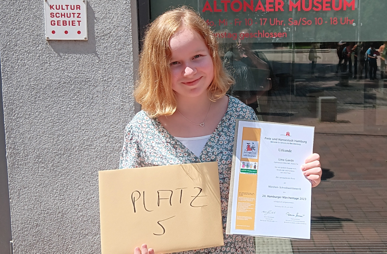 Schülerin zeigt Urkunde von Märchenwettbewerb